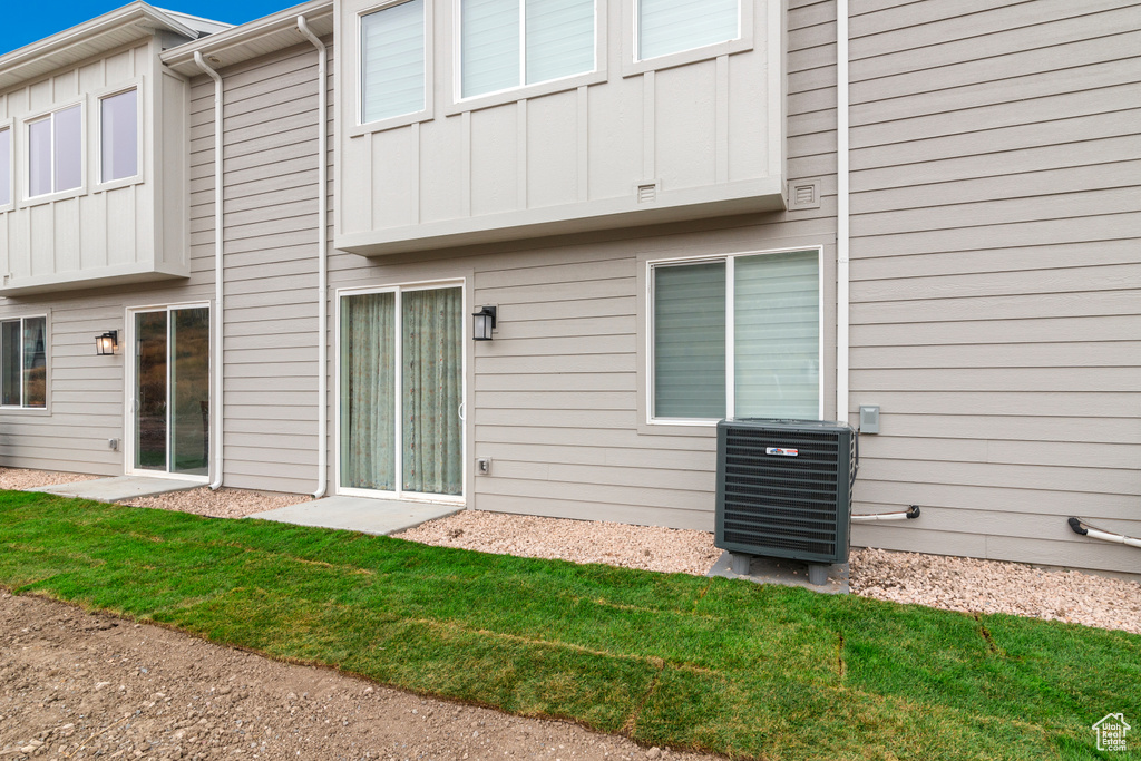 Rear view of house with board and batten siding and central AC