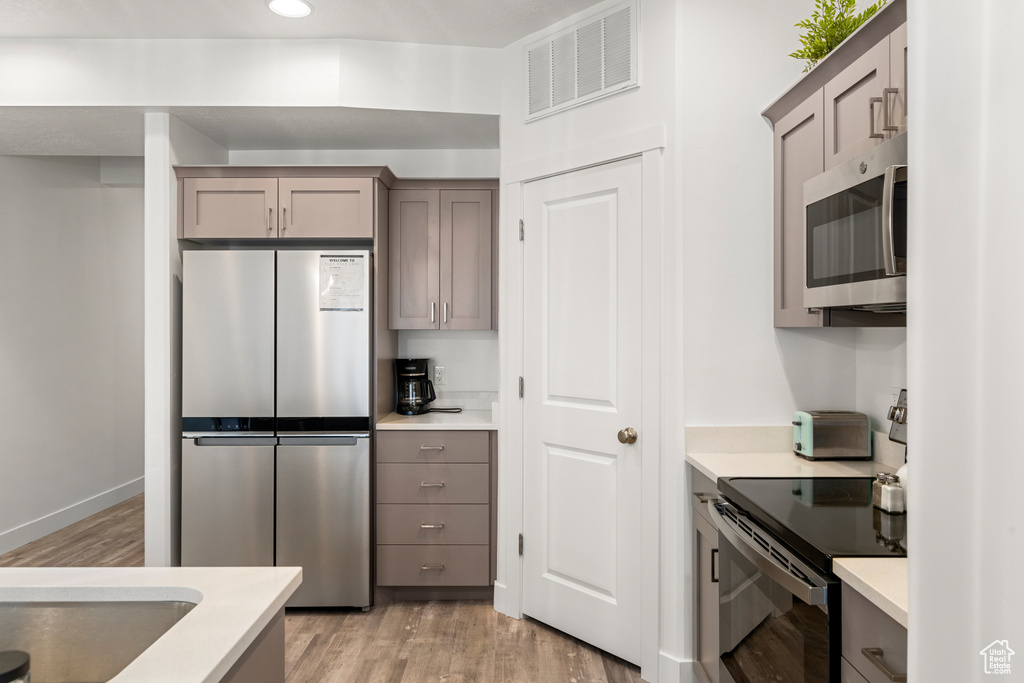 Kitchen featuring visible vents, gray cabinets, appliances with stainless steel finishes, and light wood finished floors