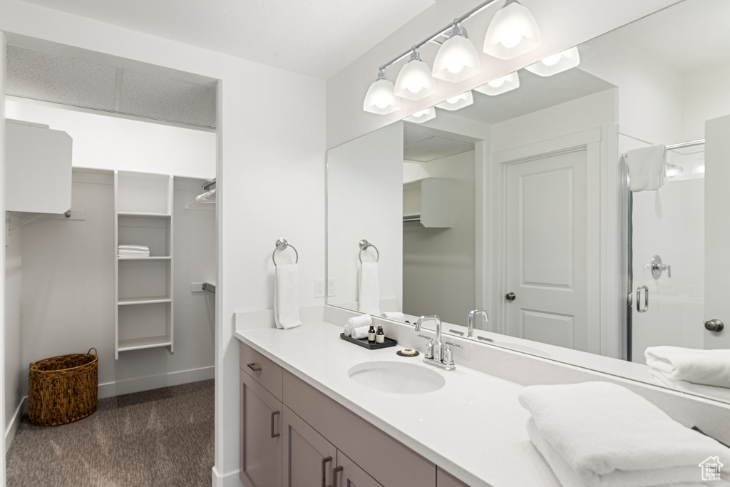 Bathroom with vanity, baseboards, a walk in closet, and a stall shower