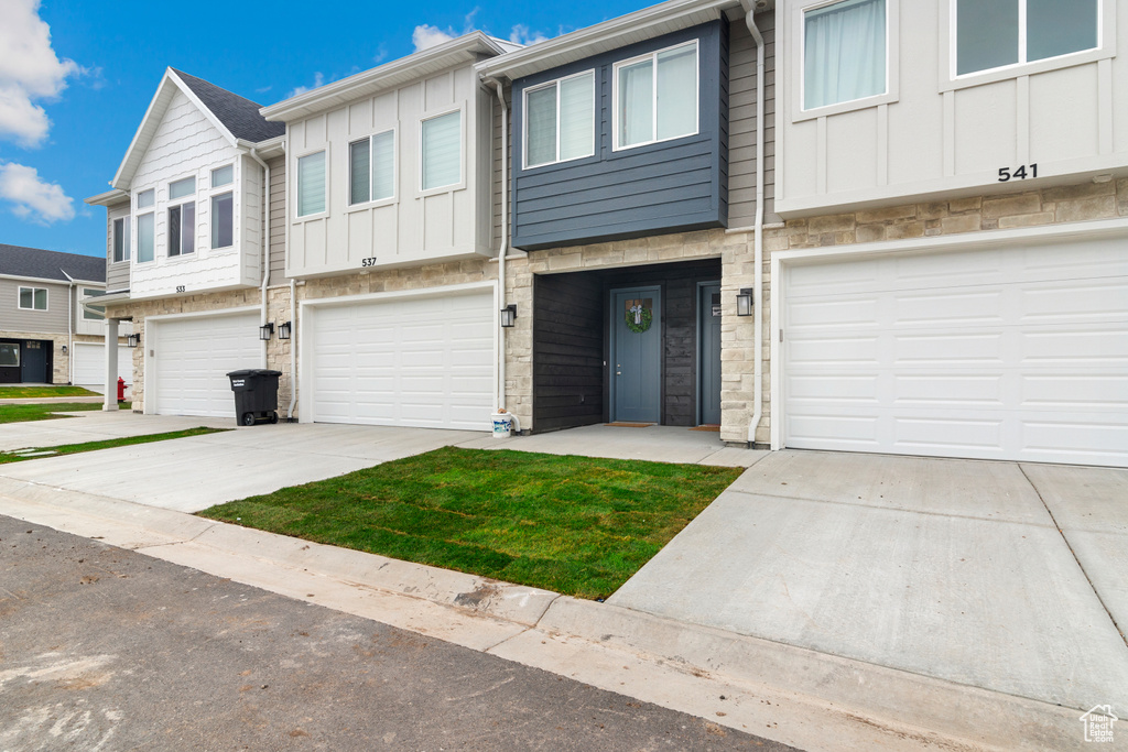 View of front of house with a garage, board and batten siding, driveway, and stone siding
