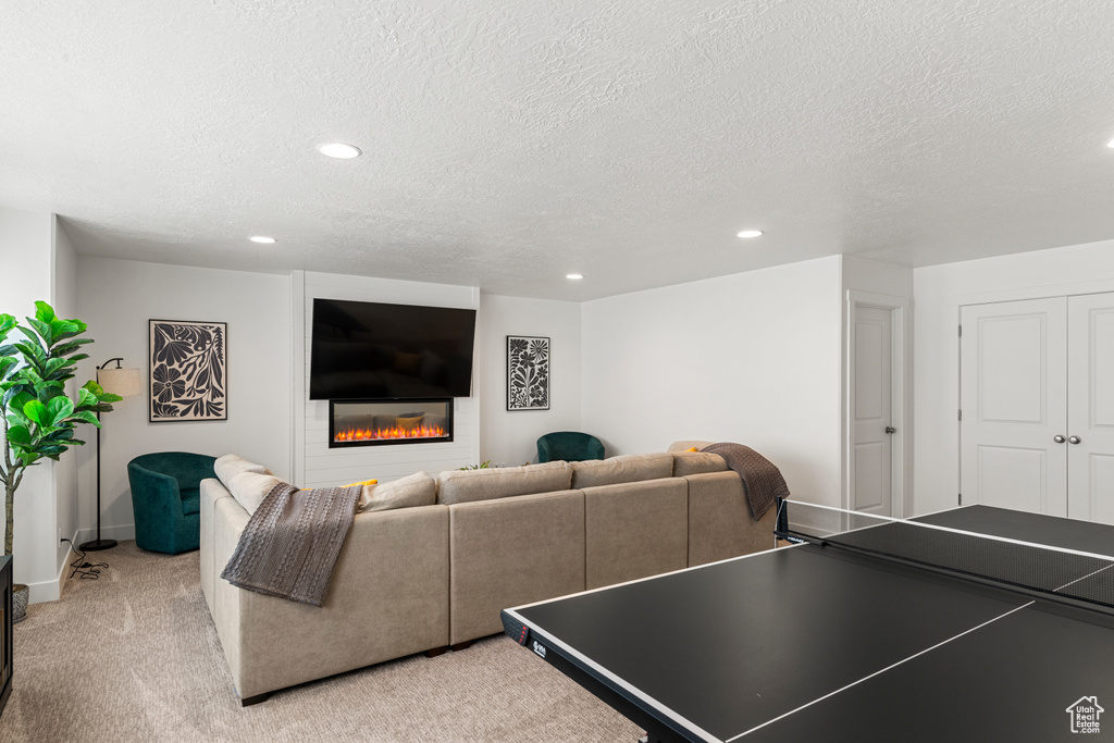 Rec room featuring recessed lighting, a textured ceiling, and a glass covered fireplace
