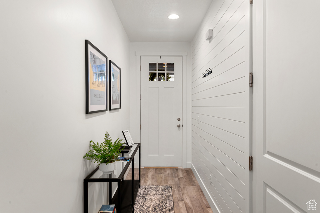 Entryway featuring light wood-type flooring, recessed lighting, and wood walls