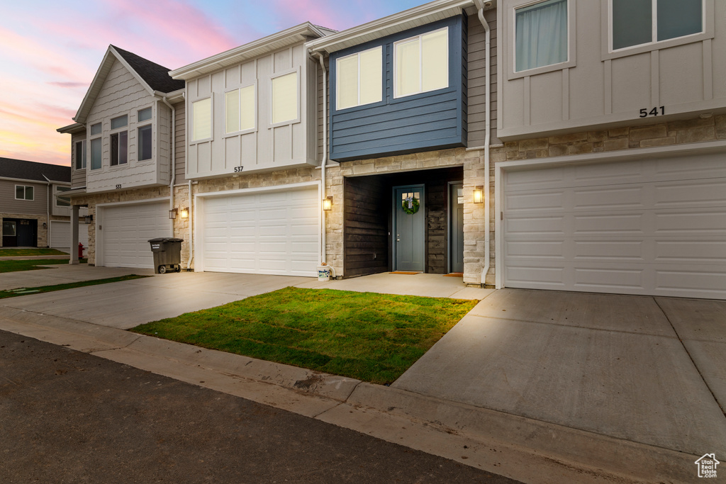 Townhome / multi-family property featuring board and batten siding, driveway, and a garage