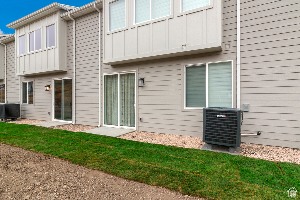 Rear view of house with board and batten siding and central AC unit