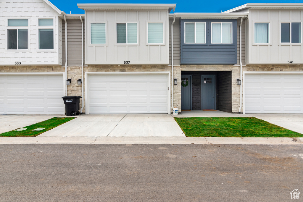 View of property with board and batten siding, an attached garage, and concrete driveway