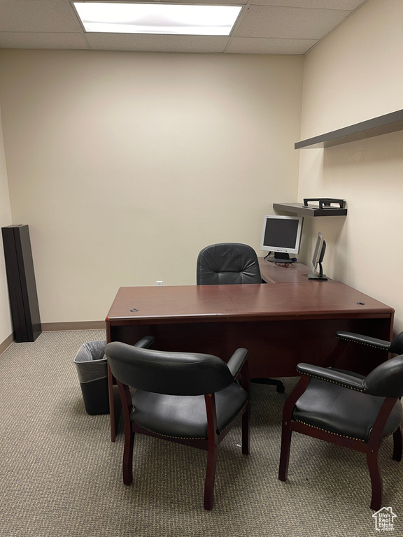 Carpeted office space featuring baseboards and a drop ceiling