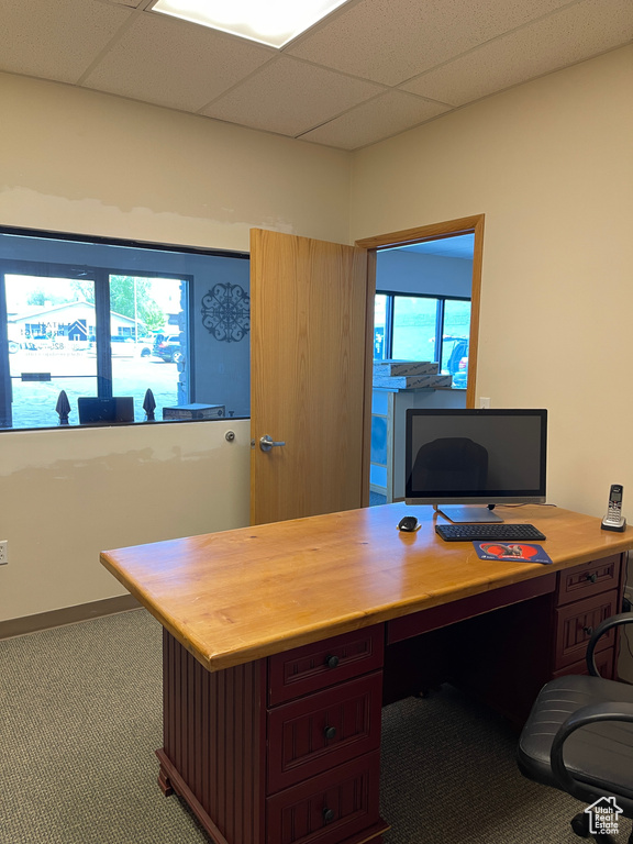 Carpeted office with a drop ceiling and built in desk