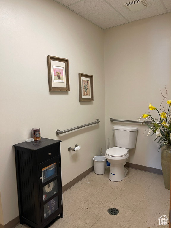 Bathroom with toilet, baseboards, visible vents, and a paneled ceiling