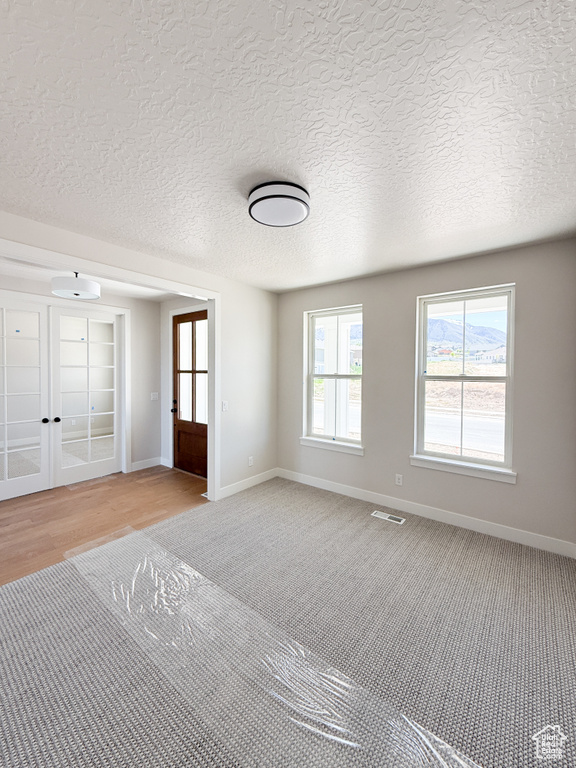Interior space featuring visible vents, baseboards, french doors, and light colored carpet