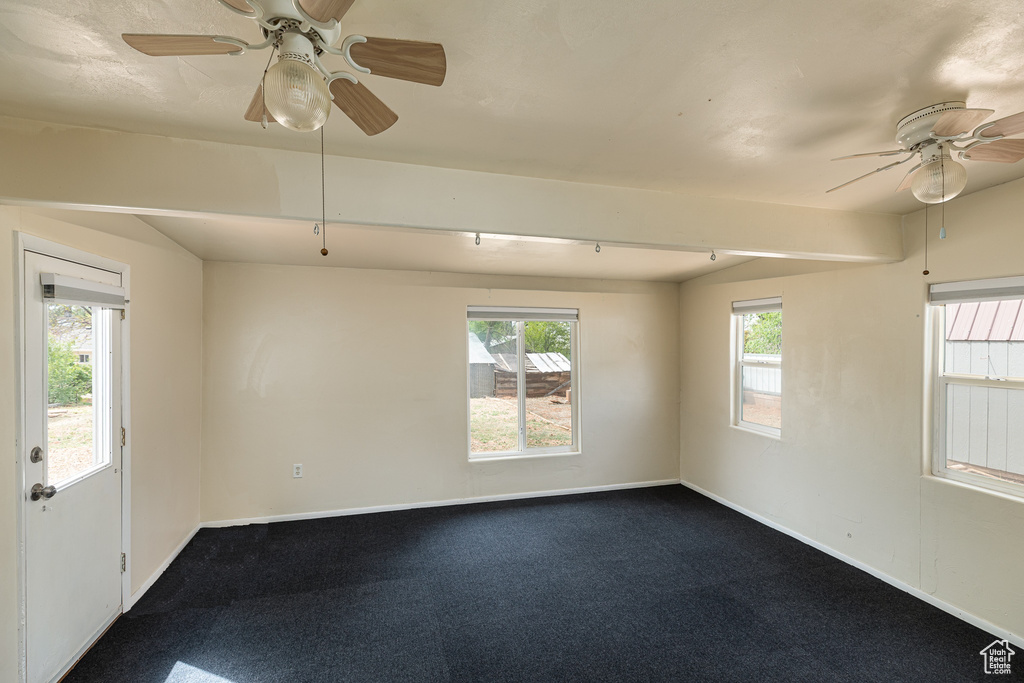Empty room with baseboards, ceiling fan, and dark colored carpet