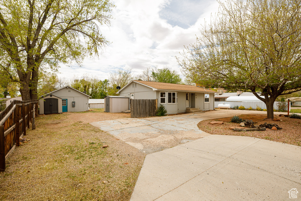 View of front of house with fence, an outbuilding, and a shed