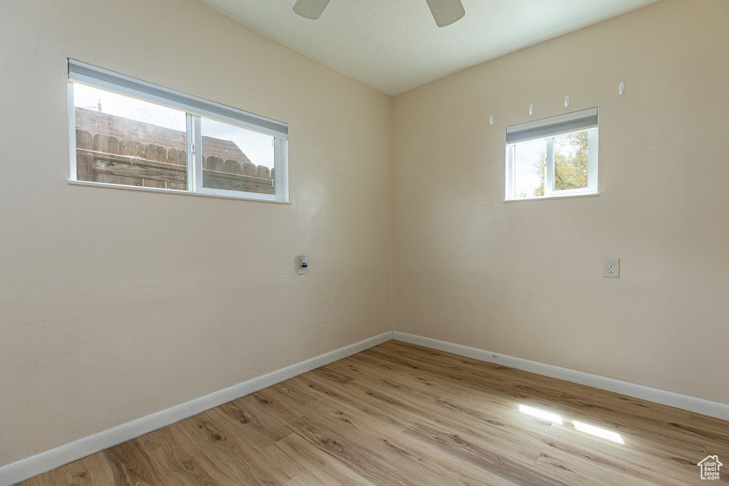 Unfurnished room with baseboards, light wood finished floors, and a wealth of natural light