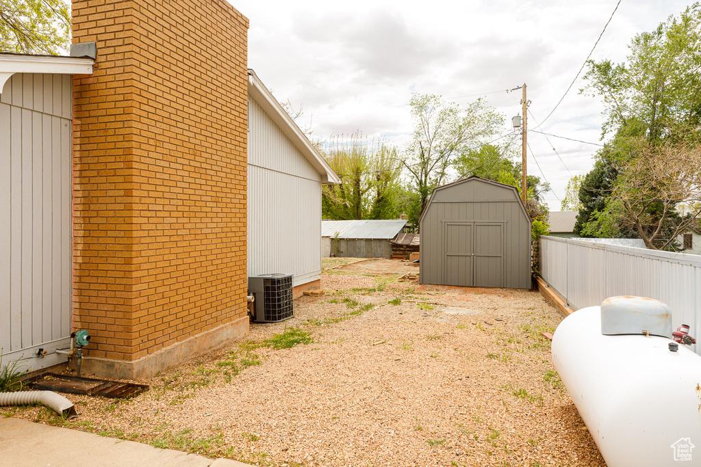 View of yard with a storage unit, an outdoor structure, fence, and cooling unit