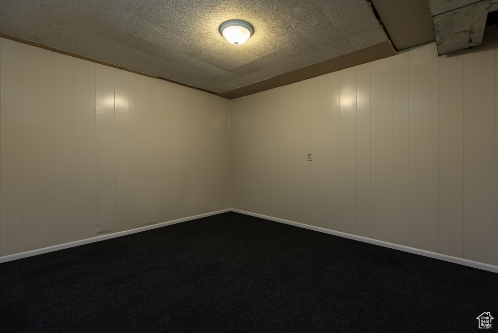Spare room featuring a textured ceiling and dark carpet