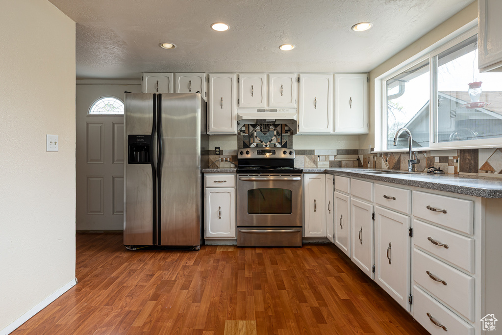 Kitchen with a sink, white cabinetry, under cabinet range hood, and stainless steel appliances