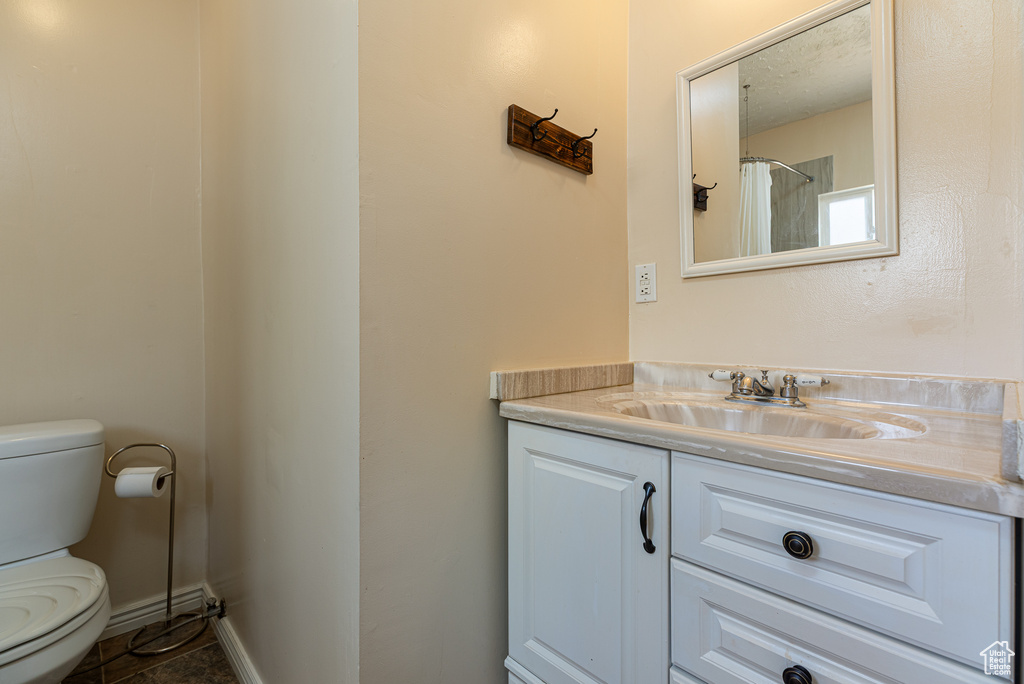 Full bath with vanity, baseboards, and toilet
