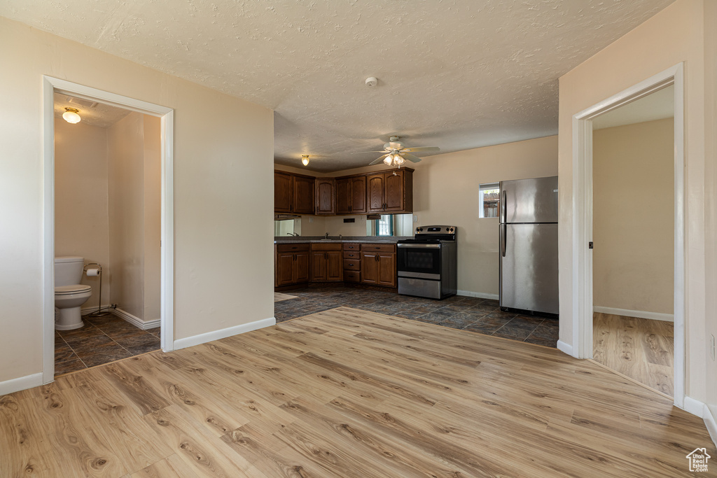 Kitchen featuring ceiling fan, stainless steel appliances, a textured ceiling, and dark wood-type flooring
