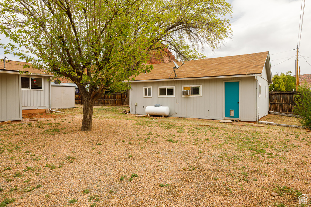 Back of house featuring an outdoor structure, a shingled roof, and a fenced backyard