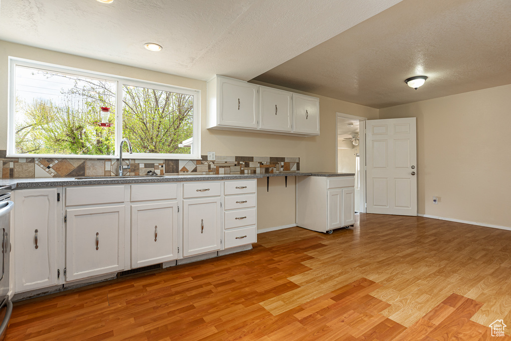 Kitchen featuring a sink, light wood finished floors, and white cabinetry