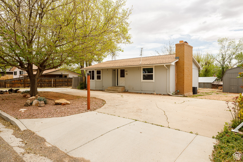 Single story home with an outdoor structure, fence, roof with shingles, a shed, and a chimney