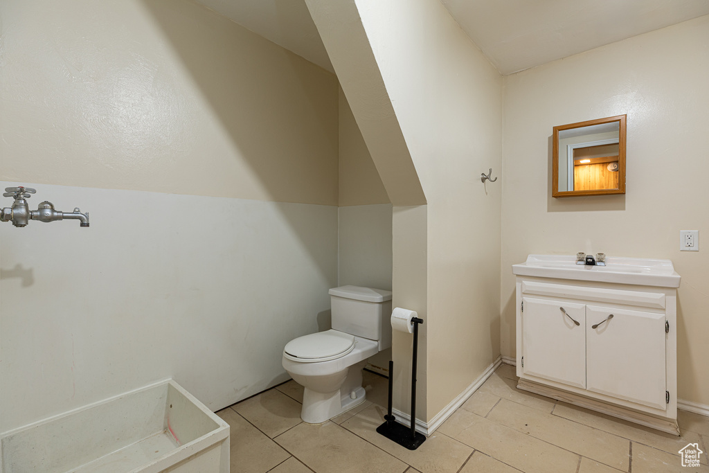 Half bathroom with vanity, tile patterned flooring, and toilet