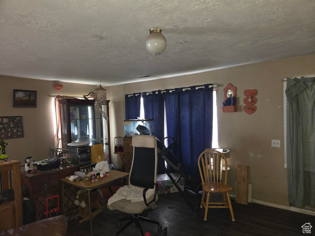 Interior space with baseboards, a textured ceiling, and wood finished floors