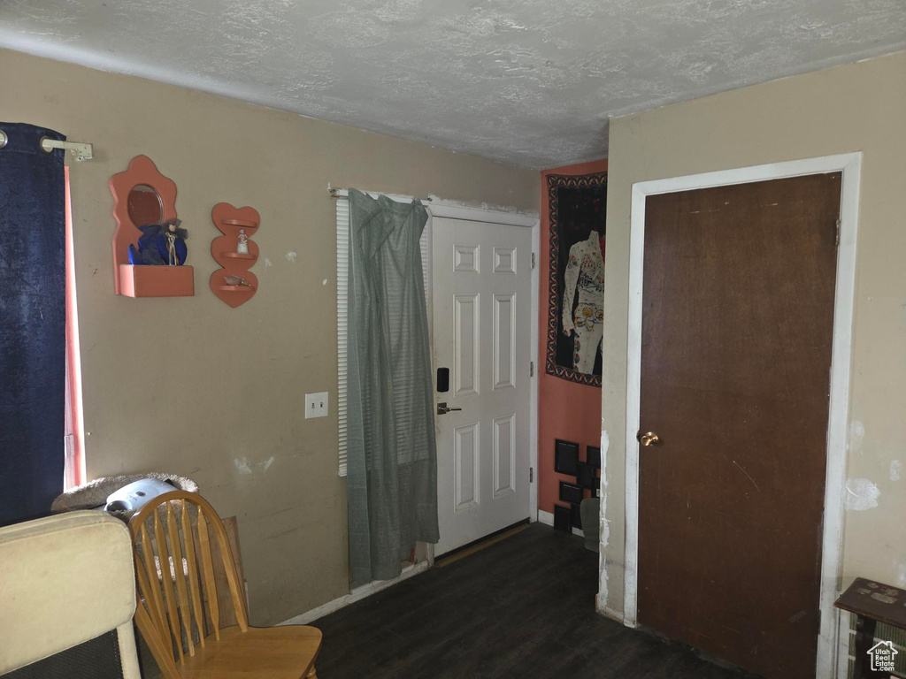Interior space with a textured ceiling, baseboards, and wood finished floors