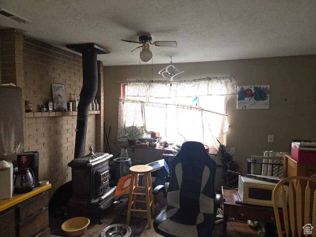 Interior space featuring a wood stove, a ceiling fan, a textured ceiling, and visible vents