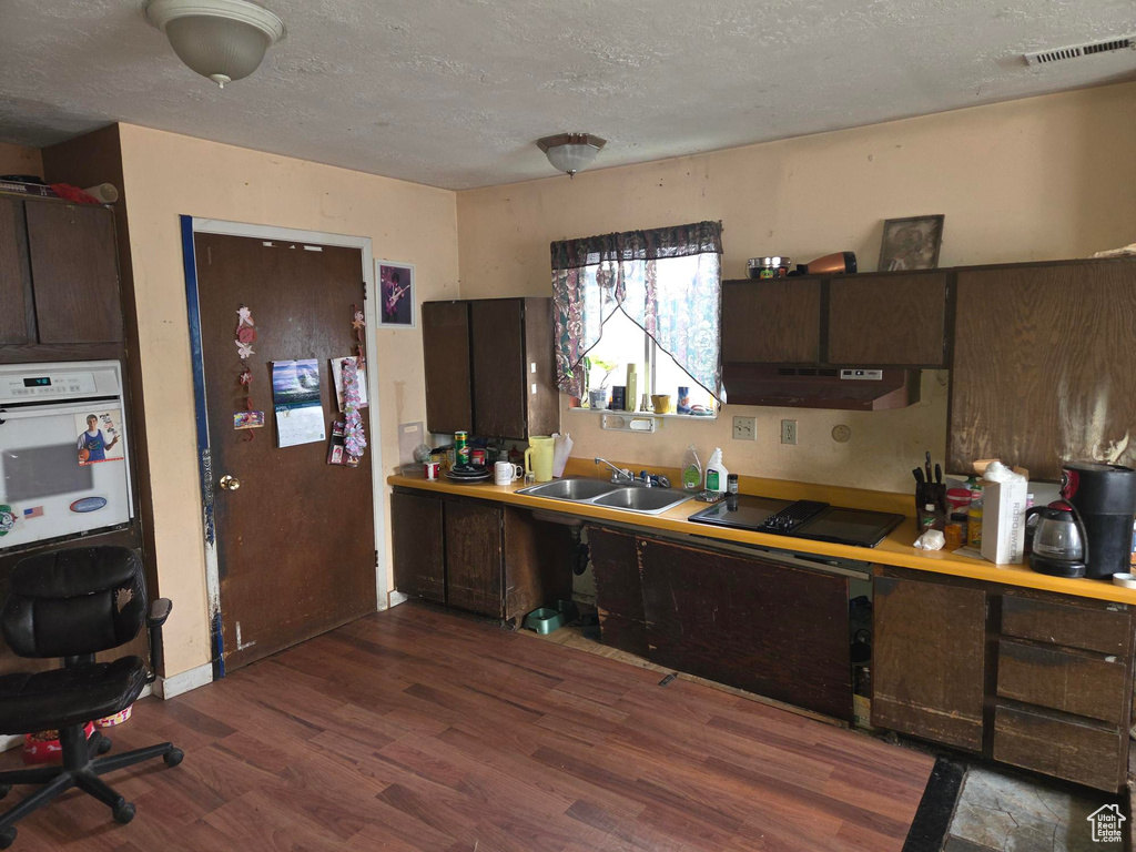 Kitchen with visible vents, a sink, black electric stovetop, under cabinet range hood, and oven
