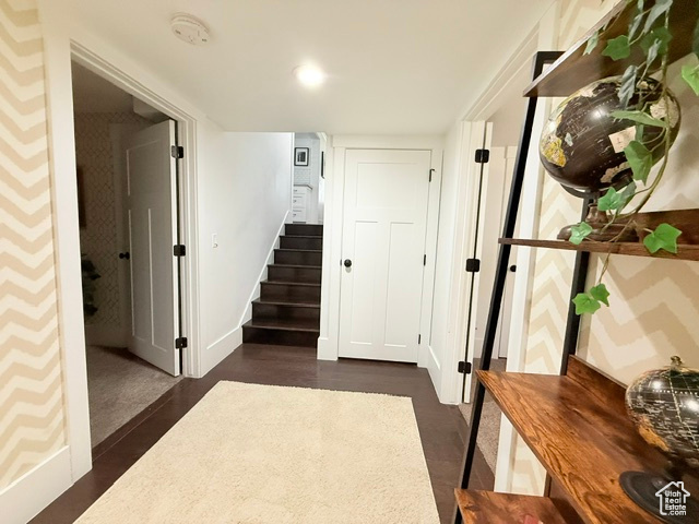 Hallway with stairway, baseboards, and dark wood-style floors