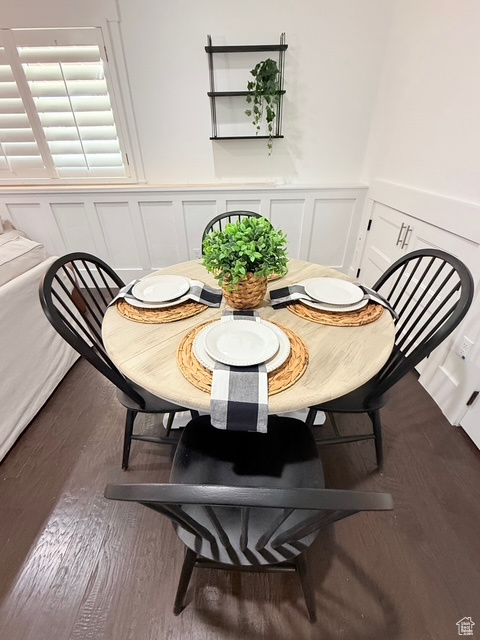 Dining area featuring a wainscoted wall, wood finished floors, and a decorative wall