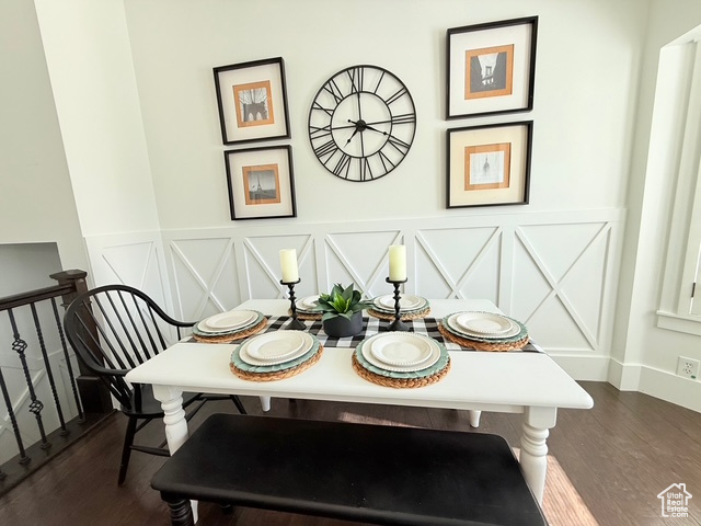 Dining room featuring wainscoting, dark wood-style floors, and a decorative wall
