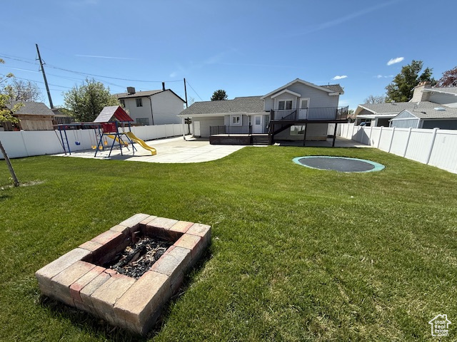 View of yard featuring a fenced backyard, a patio, a playground, and an outdoor fire pit