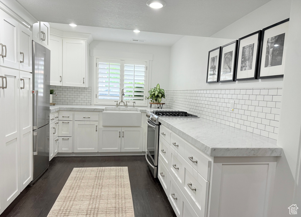 Kitchen featuring white cabinetry, appliances with stainless steel finishes, tasteful backsplash, and a sink
