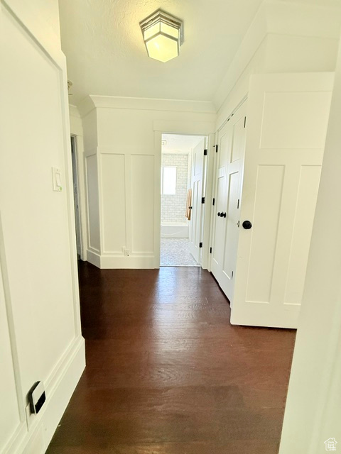 Corridor featuring a decorative wall and dark wood-type flooring