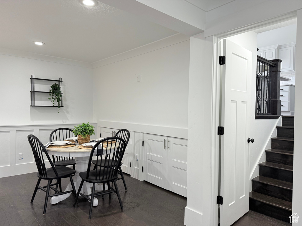 Dining space with crown molding, dark wood finished floors, stairway, wainscoting, and recessed lighting