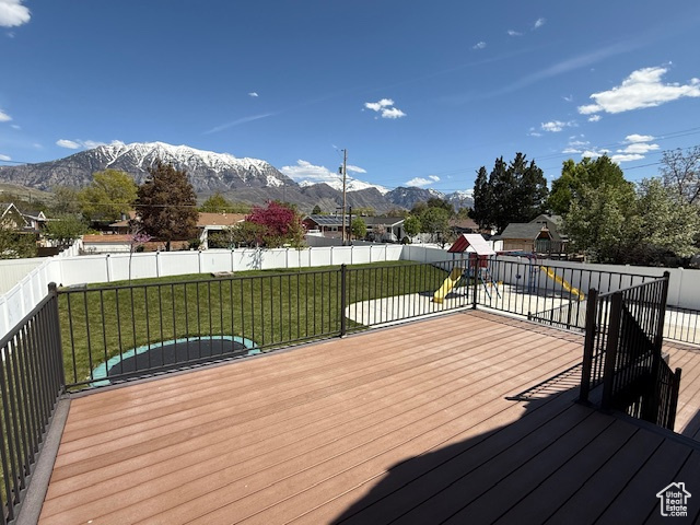 Deck featuring a lawn, a mountain view, and a fenced backyard