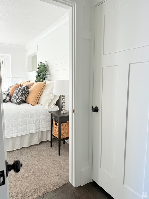 Bedroom featuring crown molding and dark wood-type flooring