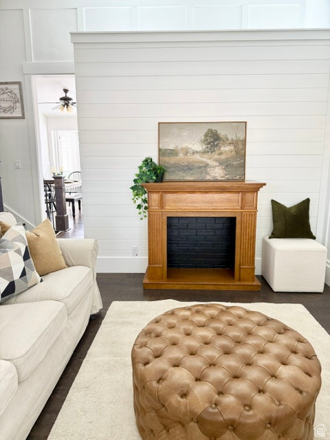 Living room with baseboards, a ceiling fan, dark wood-style flooring, and a fireplace