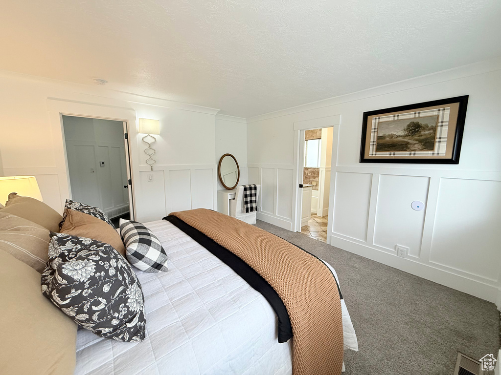 Bedroom with carpet, a decorative wall, a wainscoted wall, and crown molding