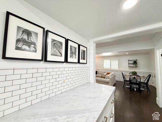 Kitchen with white cabinets, beam ceiling, dark wood finished floors, a wainscoted wall, and open floor plan