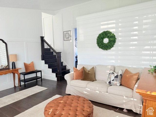 Living room with a decorative wall, wood finished floors, stairs, and wainscoting