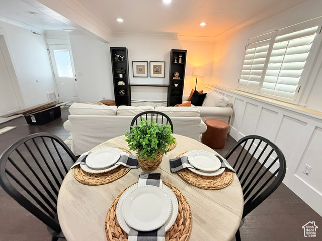 Dining area featuring wood finished floors, a wainscoted wall, ornamental molding, a decorative wall, and recessed lighting