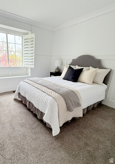 Bedroom with ornamental molding, carpet flooring, a wainscoted wall, radiator, and a decorative wall