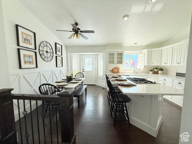 Kitchen with light countertops, a kitchen breakfast bar, a ceiling fan, white cabinetry, and a kitchen island