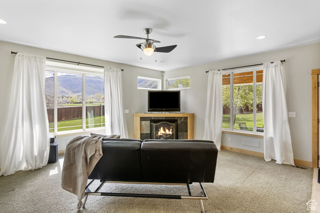 Living area featuring carpet floors, ceiling fan, and a wealth of natural light