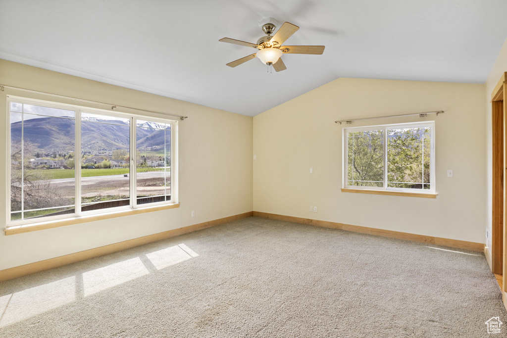 Spare room featuring carpet floors, baseboards, a ceiling fan, and lofted ceiling