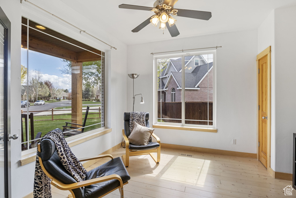 Sitting room with baseboards, a ceiling fan, hardwood / wood-style floors, and a wealth of natural light