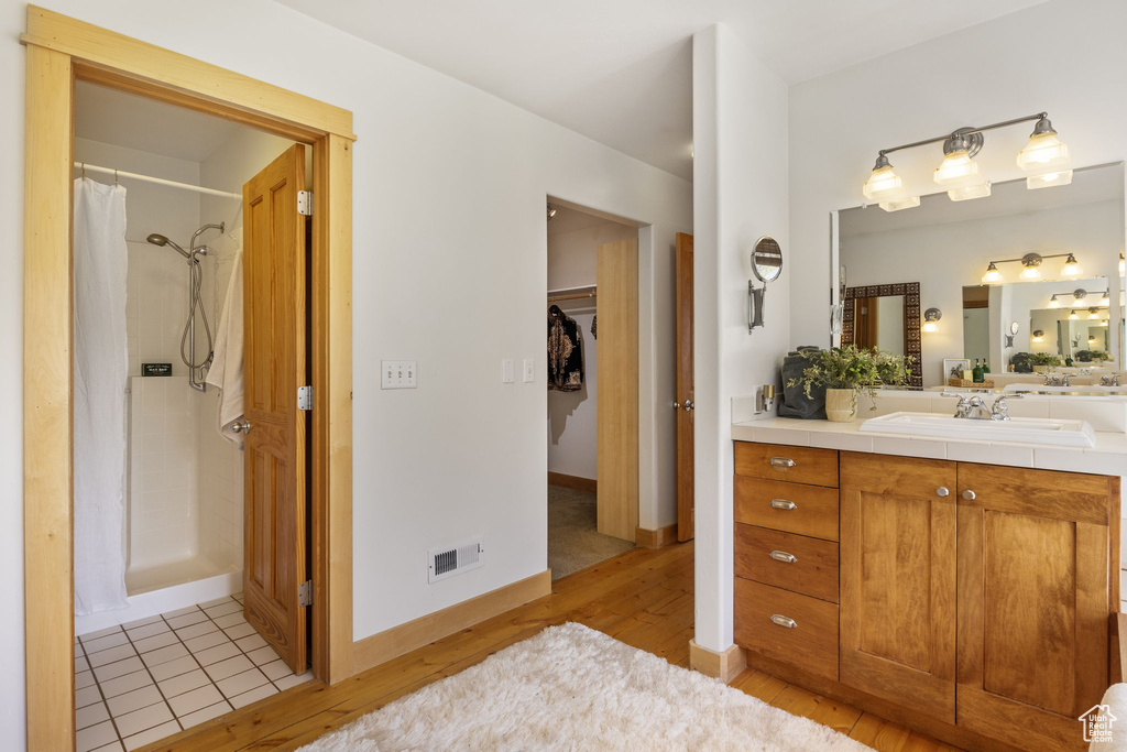 Full bathroom featuring vanity, a shower with curtain, wood finished floors, and visible vents