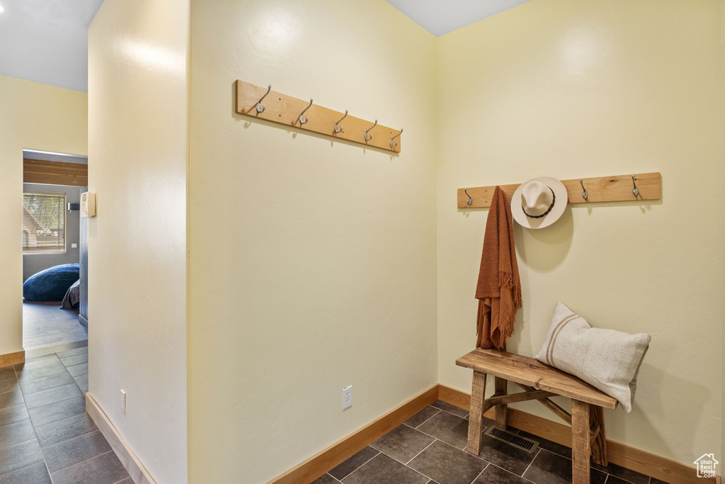 Corridor with dark tile patterned flooring and baseboards